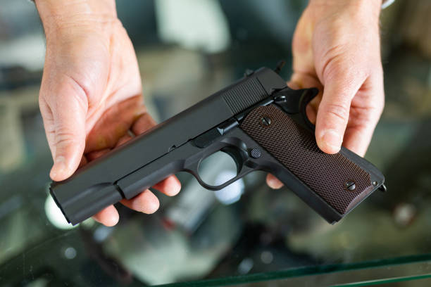istock Gunsmith shop assistant demonstrates black pistol in hands 1398682785