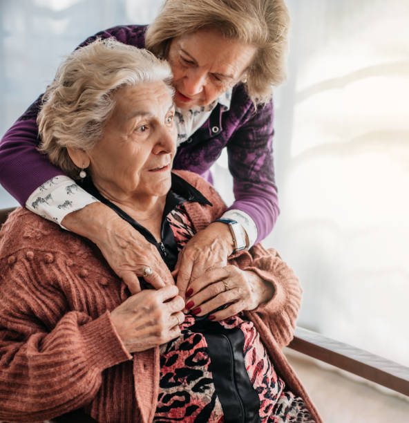 uma mulher abraça sua irmã idosa em um asilo. conceito de família e afeto na velhice. doenças mentais e degenerativas. alzheimer - 99 - fotografias e filmes do acervo