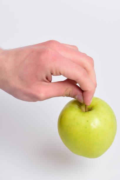 istock Male hand touches light green apple. Apple on white background 1398687386
