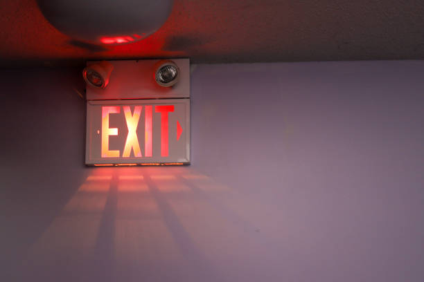 a exit sign on a white wall - emergency exit imagens e fotografias de stock