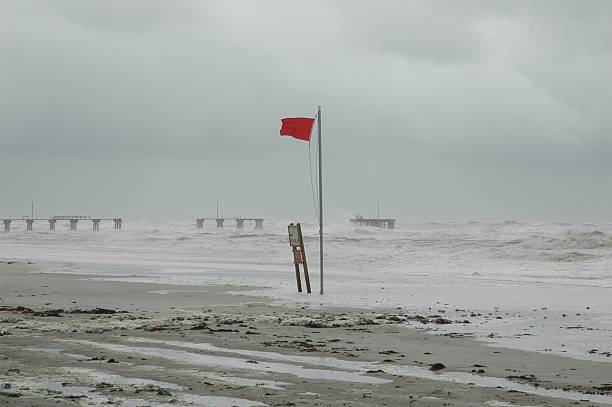 Hurricane Approaching Coast Hurricane on the coast of Alabama.  Waves crashing against damaged pier.  Red warning flag flying in the foreground. gale stock pictures, royalty-free photos & images