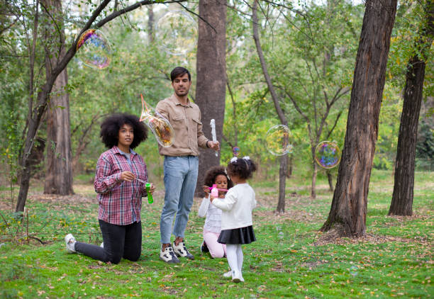 istock Happy family playing soap bubbles in park. 1398691040