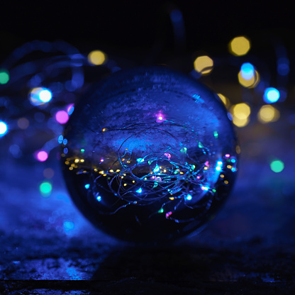 Photography of bright clear transparent  crystal ball in cold blue light on the snow. The ball like a world around. Beautiful party inside of ball. Miracle view concept. Close up photography