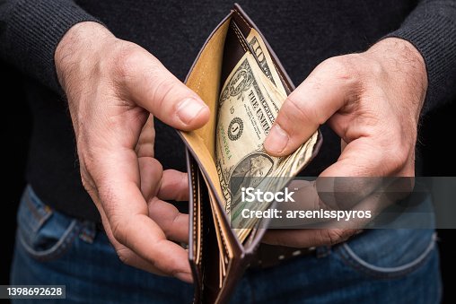 istock Hands holding a wallet with a small amount of US dollars, close up 1398692628