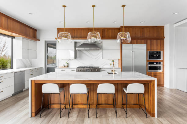 beautiful kitchen in new luxury home with waterfall quartz island, pendant lights and hardwood floors. - binnenopname fotos stockfoto's en -beelden