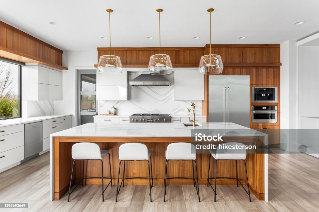 Beautiful kitchen in new luxury home with waterfall quartz island, pendant lights and hardwood floors. kitchen in newly constructed luxury home Kitchen Stock Photo