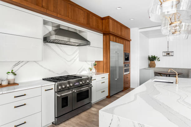 Beautiful kitchen in new luxury home with waterfall quartz island, pendant lights and hardwood floors. kitchen in newly constructed luxury home quartz stock pictures, royalty-free photos & images