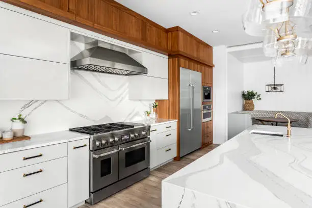 Photo of Beautiful kitchen in new luxury home with waterfall quartz island, pendant lights and hardwood floors.