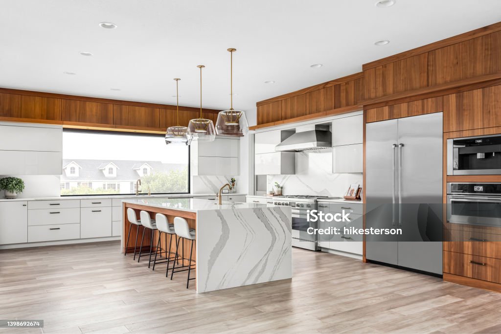 Beautiful kitchen in new luxury home with waterfall quartz island, pendant lights and hardwood floors. kitchen in newly constructed luxury home Kitchen Stock Photo