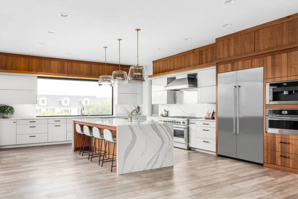 Beautiful kitchen in new luxury home with waterfall quartz island, pendant lights and hardwood floors. stock photo
