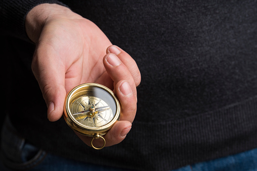 Hand holding a vintage compass with copy space, close up, selective focus