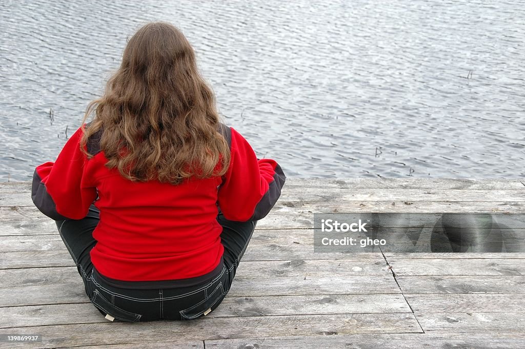 Yoga Blonde sitting cross-legged on the jetty. She is lost in meditation. Blond Hair Stock Photo