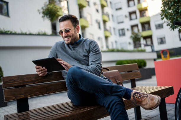 istock Handsone Man sitting on bench and working on digital tablet 1398699474