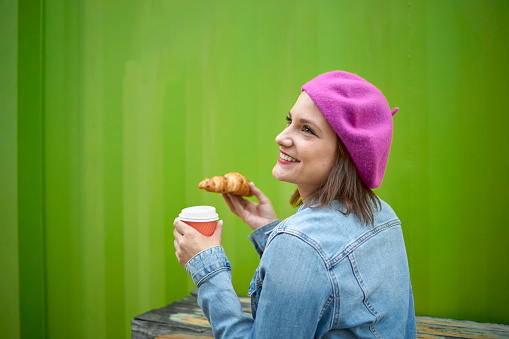 Woman bite croissant outdoor bar breakfast with green backgorund