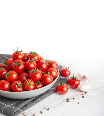 plate with cherry tomatoes and spices on white marble background
