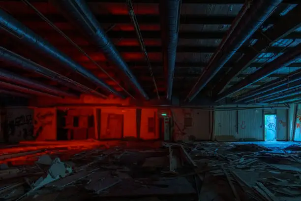 Photo of inside an old industrial military base hall with broken electric switch cabinets and pipes at the ceiling