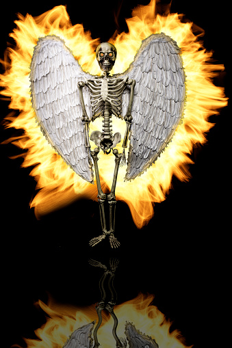 Dramatic portrait of a angel in the form of a skeleton with wings on fire