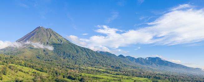 Arenal Vulcano, Fortuna, Costa Rica - May 22, 2022: A panoramic view of Arenal Vulcano. Costa Rica's best known vulcano. It's a stratovolcano – a large, symmetrical volcano that’s built upon layers of ash, rock and lava – and at 5,437 feet (1,657 meters), it stands high above the rest of the countryside. Arenal was active from 1968 to 2010 and was in that period the tenth most active vulcano on Earth.