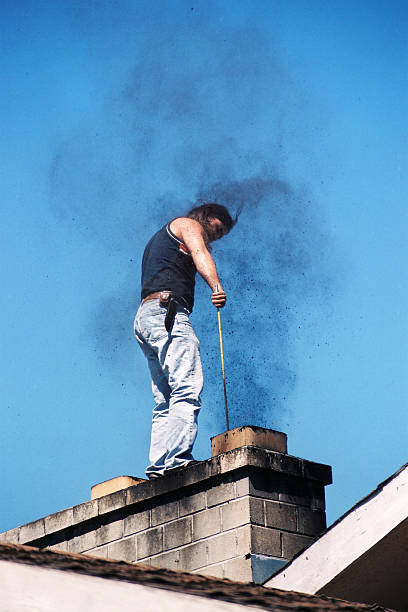 Young man cleaning the chimney Young man standing on the roof of the house,cleaning the chimney noah young stock pictures, royalty-free photos & images