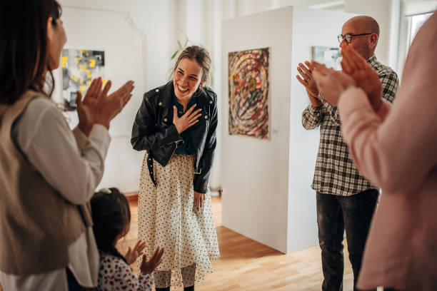 People applauding at gallery opening People are applauding to a young female artist at gallery opening. gallery opening stock pictures, royalty-free photos & images