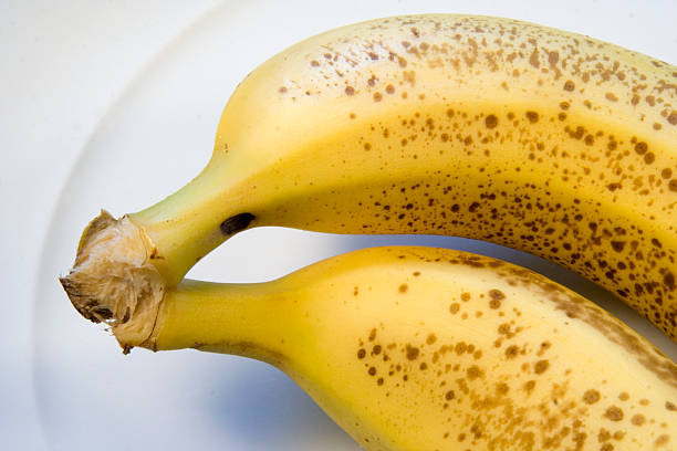 deux bananes sur plaque blanche - moving up fruit close to togetherness photos et images de collection