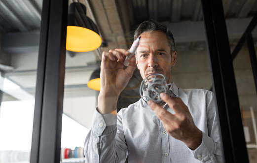 Latin American designer working at a creative office on a model to print in 3D and drawing on glass  - innovation concepts