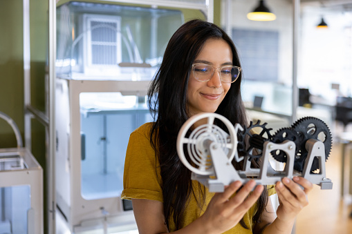 Latin American female designer holding a 3D printed model at a creative studio