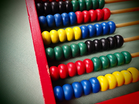 Education concept - abacus with many colorful beads. Red, blue, green, black, yellow details on the abacus. Mathematical exercises. School program.