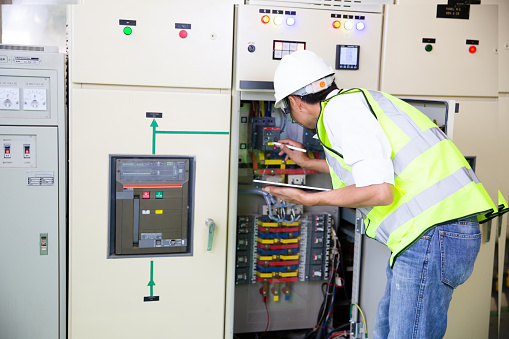 Maintenance engineers inspect relay protection system. Bay control unit. Medium voltage switchgear