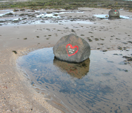 Rock/bolder with a red heart and I love you painted on it on a sandy beach. Nikon coolpix E7900