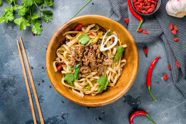 istock fried Udon with beef and vegetables on wooden bowl on grey table top view 1398727841