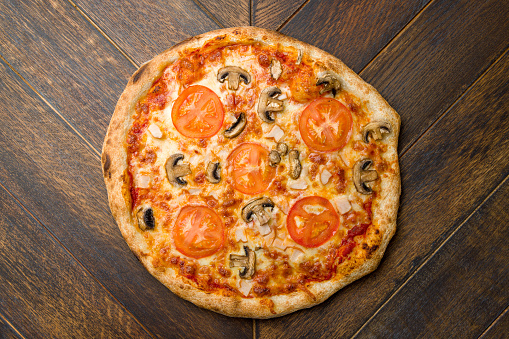 pizza with mushrooms and tomatoes on wooden table top view