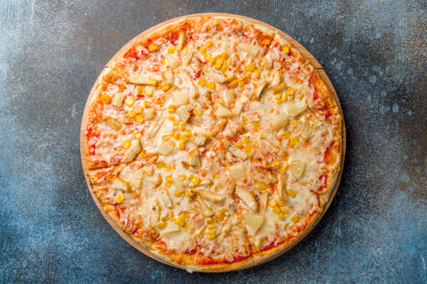 istock pizza Hawaiian with pineapple and chicken with cheese and corn top view on dark blue stone table 1398727886