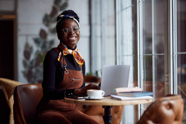 A multicultural student girl sits in a coffee shop and following online lecture on the laptop. stock photo