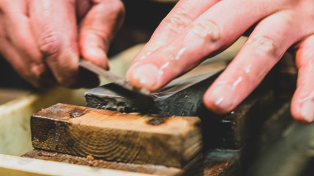 istock Master swordsmith is sharpening knife on grindstone with water 1398732833