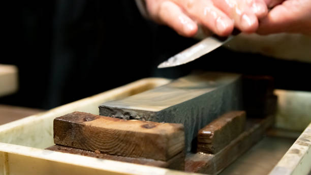 istock Master swordsmith is sharpening knife on grindstone with water 1398732834