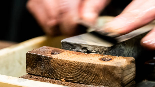 istock Master swordsmith is sharpening knife on grindstone with water 1398732835
