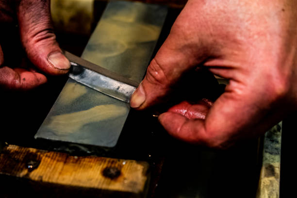 istock Master swordsmith is sharpening knife on grindstone with water 1398732845