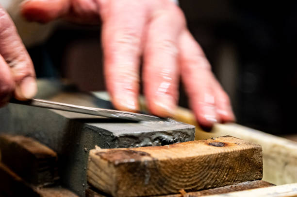 istock Master swordsmith is sharpening knife on grindstone with water 1398732848