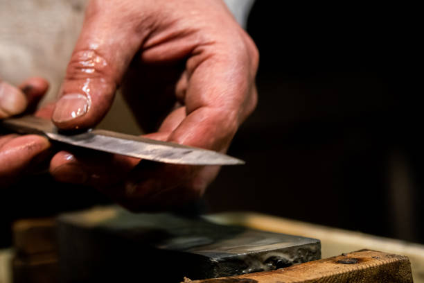 istock Master swordsmith is sharpening knife on grindstone with water 1398732849