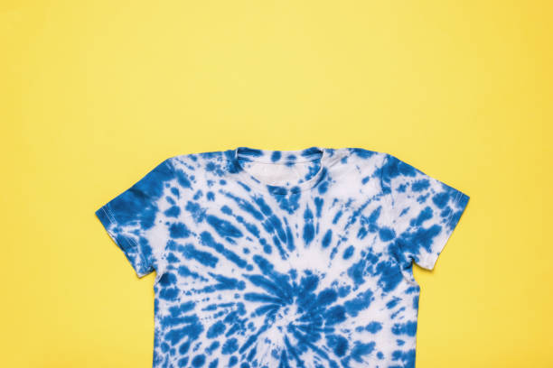 istock Blue tie dye T-shirt on a yellow background. Flat lay. 1398733951