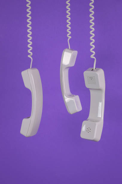 istock Three handsets hanging on wires on a purple background. Minimal concept. 1398733999