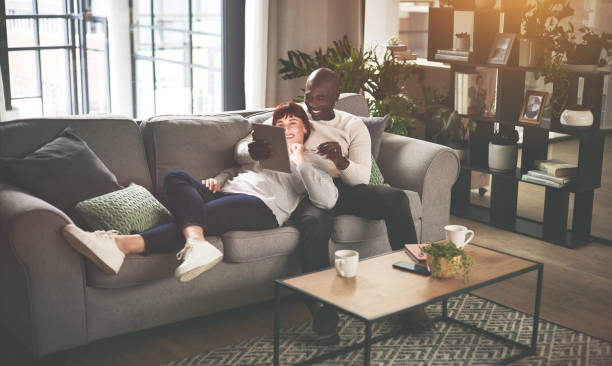istock A couple using a digital tablet while relaxing on the sofa at home. A happy young man and woman browsing online with a touchscreen on the couch 1398736187