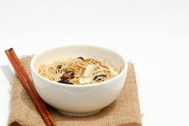 Vegan meal, noodle with shiitake and tofu in white bowl. Isolated, white background.