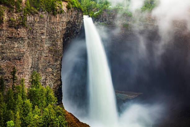 Close up of large powerful waterfall flowing into dark river basin