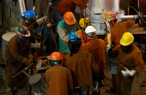 Busy Workers - Workers swarm around bull ladle (crucible) and ladle at iron pour event