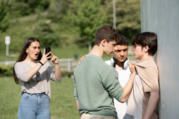 Two bullies menacing teenager boy and filming on phone Two bullies menacing teenager boy and girl filming on phone. Cyber bullying and violence concept. bullying stock pictures, royalty-free photos & images