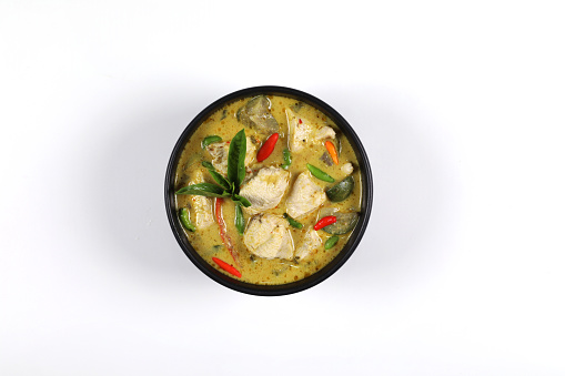 Thai food. Chicken green curry put in a black bowl isolated on white background. chicken breast, coconut milk, brinjal, curry paste, basil, kaffir lime leaves, garden paprika. Top view have copy space.