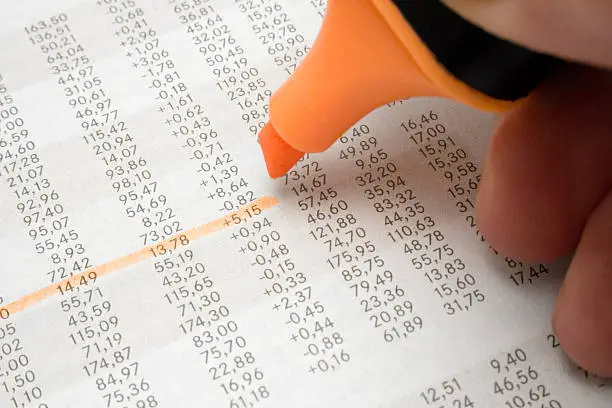 Marking business numbers in a financial newspaper.