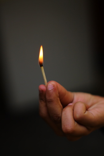 Burning match stick in the hand of indian and pakistani boy's hands with dark background